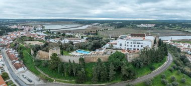 Portekiz 'deki Sado nehrinin yukarısındaki ortaçağ şatosunun kare kuleleri ile Alcacer' in havadan görünüşü, saray otelden otele dönüşür.
