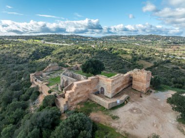 Taştan duvarlar ve çentikli duvarlar Paderne Kalesi 'nin mavi gökyüzüne karşı tarihi bir Portekiz kalesi olan ortaçağ mimarisini tanımlıyor