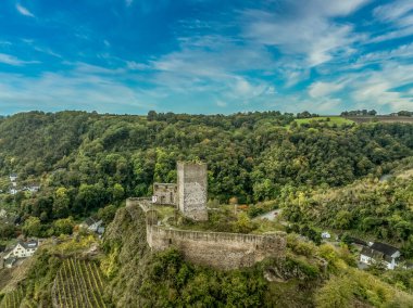 Moselle nehri üzerindeki Niederburg tepesi Gotik kalesinin havadan görünüşü kare donjon, dairesel savunma duvarı, mavi gökyüzü.