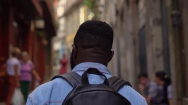 Genç Afro-Amerikan gezgin sırt çantalı rahat Avrupa şehrinde yürüyor. Arka görünüm.