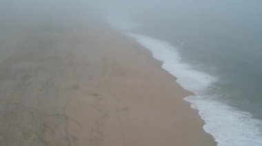 Okyanus kumsalındaki kumlu kumullar soğuk deniz dalgalarının yanında, sahilde. Sakin atmosfer.