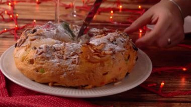 Kadın eli Portekiz Bolo Rei 'den bir parça kesiyor. Geleneksel bir Noel pastası. Meyveli ve kremalı.