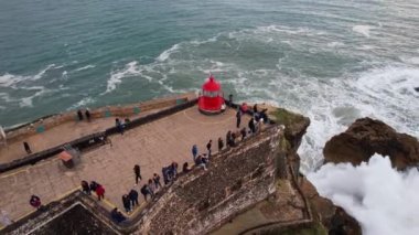 Portekiz, Nazare 'deki Sao Miguel Arcanjo Deniz Feneri Kalesi' ndeki insanların Çember Havadan görüntüsü. Nazare, dünyanın en büyük dalgalarına sahip olmasıyla ünlüdür..