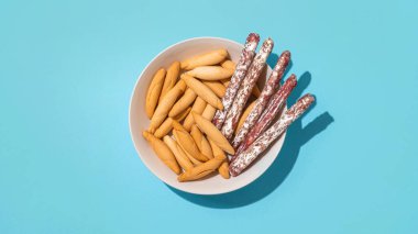 Mini fuet ve picos 'un üst görüntüsü - açık mavi arkaplanda koyu gölgeli ekmek çubukları