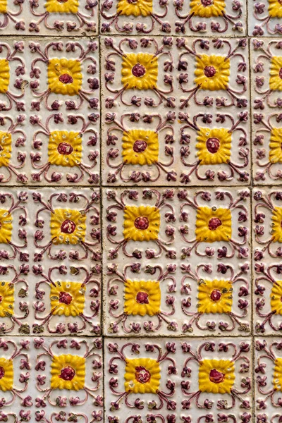Fragment of building wall with yellow floral ceramic wall tiles Azulejo Abstract decorative background textured ornate pattern. Traditional ornate Portuguese architecture