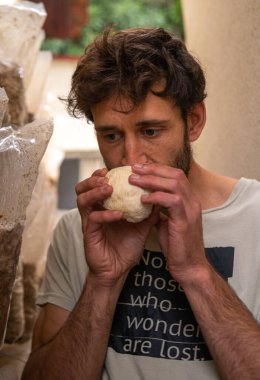 Portrait of young hispanic man sniffing lion mane mushroom on the mushrooms farm