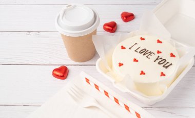 Bento cake with text I love you, on white wooden planks background. Korean style cakes in a box for one person and coffee cup