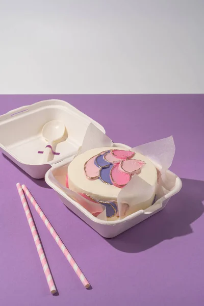 Bento mini cake as a gift for the holiday on minimalistic purple and white background. Korean style cakes in a box for one person