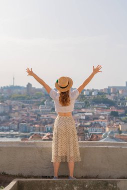 Avrupa 'da tatilin tadını çıkaran genç turist kadın, eski Avrupa kentinin manzarasına karşı ellerini kaldırdı.