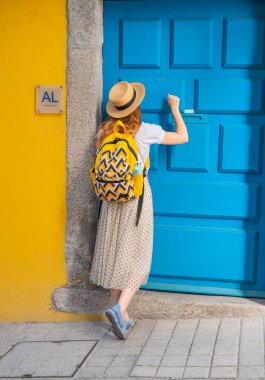 Portekiz 'de Alojamento yerel konaklamanın kapısını çalan genç turist kadının arkadan görünüşü. Avrupa 'da tatilin tadını çıkarıyor.
