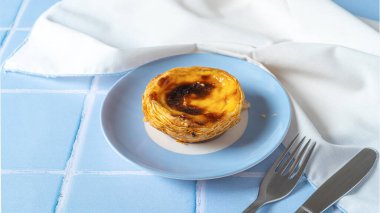 Geleneksel Portekiz yumurtalı tart tatlısı Pasteis Pastel de nata mavi tabakta. Seçici odak.