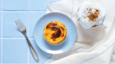 Geleneksel Portekiz usulü yumurtalı tart Pasteis Pastel de nata ya da Pastels de Belem, üzerinde bir fincan kapuçino kahvesi ve çatal olsun. Düz yatıyordu