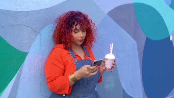 拥有一头彩色头发的快乐女性 有着蓝色抽象背景的牛奶鸡尾酒和智能手机 — 图库视频影像