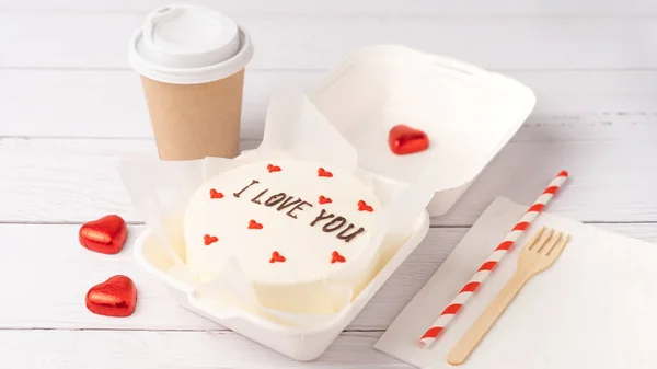 Bento cake with text I love you, on white wooden planks background. Korean style cakes in a box for one person and coffee cup