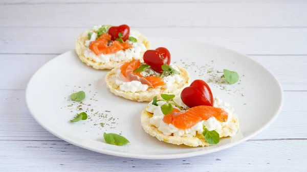 Healthy corn cake with cream cheese, salmon and Cherry tomatoes shaped of heart on the white plate. Valentine menu concept