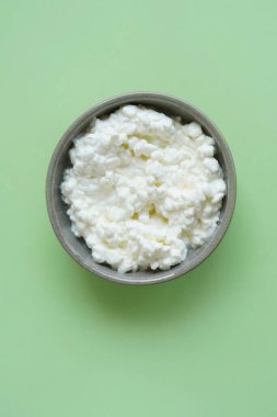 Süzme peynirin üst görüntüsü veya yeşil arka planda kasede queijo freski