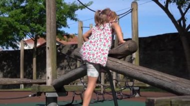 5 yaşındaki bir kız çocuğu, eko ahşap oyun parkına tırmanıyor.