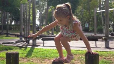 5 yaşındaki bir kız çocuğu, eko ahşap oyun parkına tırmanıyor.