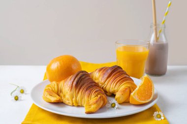 Portakal suyu ve çikolatalı sütle birlikte taze pişmiş portakallı Brioche kruvasanları. Tipik Portekiz kahvaltısı.