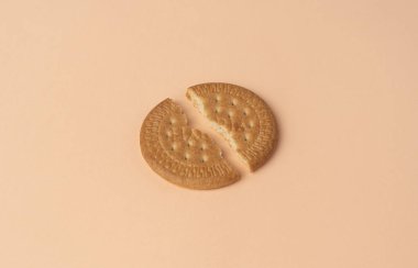 Pembe bej arka planda iki parça Maria bisküvisi. 2024 yılının moda rengi - Şeftali Tüyleri.