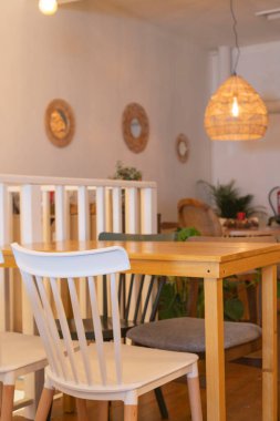 Kafenin arka planında beyaz ve ahşap masalar var.. 