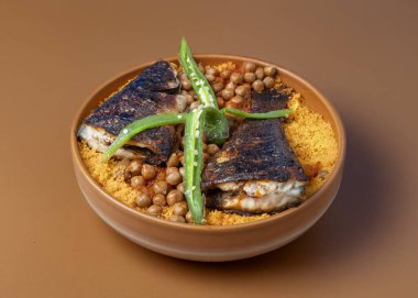 Tunisian dish - Couscous with fried seabass fish on a brown plate clipart