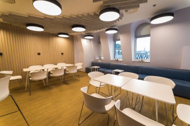 Bölge beyaz tuğla duvarlar ve beton sütunlarla bir çatı katı tarzında ofiste toplantı. Bölgede sandalyeler gri ve bölümleri cam büyük bir ahşap masa ile yok. Yukarıdaki tabloda bir projektör yoktur.