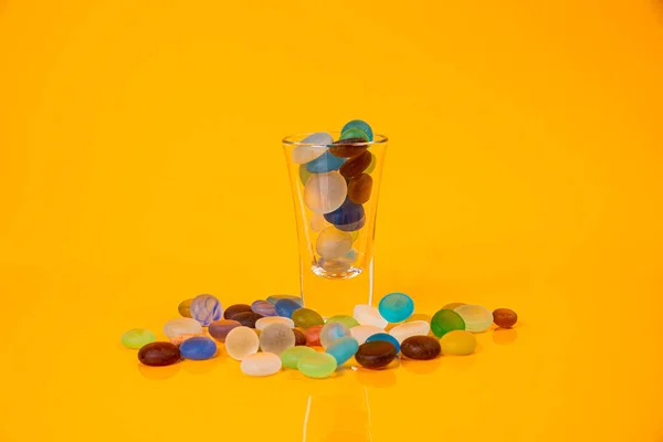colored stones in glass in jar in bucket on orange background isolated