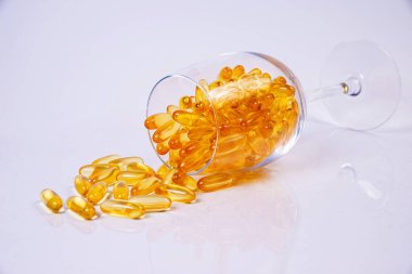 Balık yağı kapsülleri. Koyu siyah kavanozda sarı omega 3 hapları. Cam içinde balık yağı kapsülleri. Kavanozda Kova ampulleriyle. Wgite 'de izole edilmiş