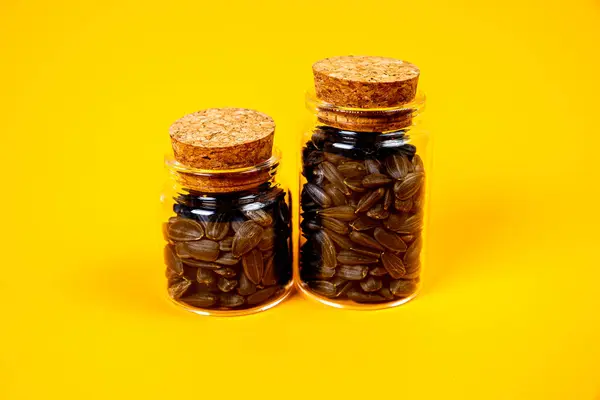 stock image white sunflower seeds in glass jar. in bucket sunflower seeds on black background. concept white sunflower seeds