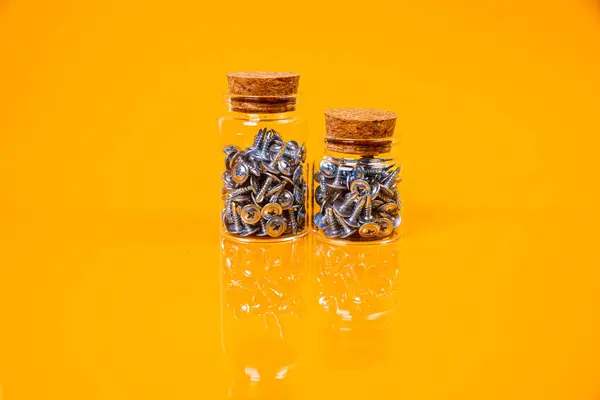 stock image Many metal self-tapping screws made of steel in a glass, in bucket jar. self-tapping screw for metal, for iron, chrome-plated self-tapping screw, on an orange yellow background, space for text