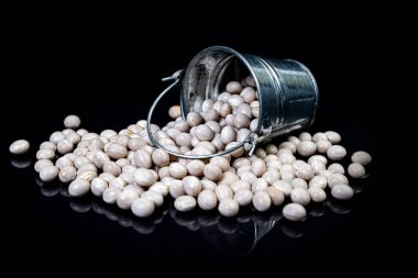 Cam kavanozda çiğ fasulye, şarap kadehi. Kovayla. Siyah arka planda çiğ beyaz fasulye. Ham beyaz fasulye, elden düşmüş, siyah üzerine izole edilmiş.