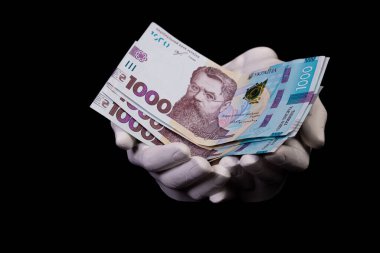 Hryvnias ile iki el. Yakın plan kadın eli kara arka planda izole edilmiş bir şey için para veriyor, sayıyor, ödüyor, Hryvnias ile alışveriş yapıyor, yolsuzluk yapıyor, siyah üzerine Hryvnias banknotlarını sayıyor