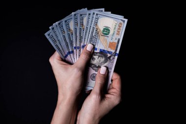 Dolarlı iki el. Yakın plan kadın eli kara arka planda izole edilmiş bir şey için para veriyor. Sayım, ödeme, dolarla alışveriş, yolsuzluk, siyah arka planda dolar banknotları saymak.