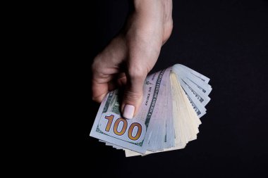 Dolarlı iki el. Yakın plan kadın eli kara arka planda izole edilmiş bir şey için para veriyor. Sayım, ödeme, dolarla alışveriş, yolsuzluk, siyah arka planda dolar banknotları saymak.