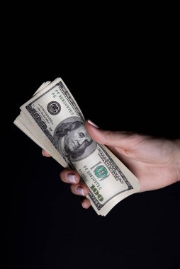 Dolarlı iki el. Yakın plan kadın eli kara arka planda izole edilmiş bir şey için para veriyor. Sayım, ödeme, dolarla alışveriş, yolsuzluk, siyah arka planda dolar banknotları saymak.