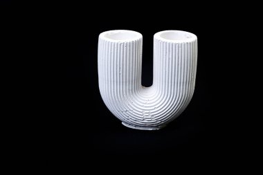 Alçıtaşı sütunlu bir kâse, çiçek süsü şeklinde bir vazo, antika bir sütun şeklinde alçı vazo. Modern sanat. Siyah bir arkaplanda modern tasarım izole edildi