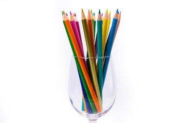 Şarap kadehi ve kovada çok renkli kalemler. Seçici renk seçici, modern sanatın izole edilmiş beyaz veya siyah arka planında bir şarap kadehinde bir grup renkli kalemi bulanıklaştırdı. Modern tasarım