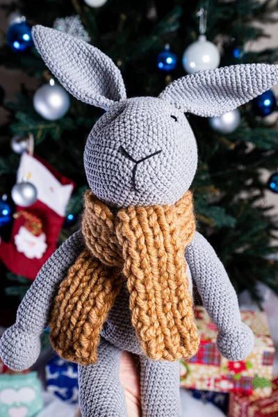 stock image knitted elk. cute moose. toy against the background of a New Year's garland, knitted hare and elk on a Christmas tree with gifts