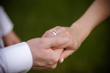 Yüzüklü gelin ve damadın elleri. Gelin ve damat bir kafede. Ahşap bir masada düğün buketi. Gelin ve damat birbirlerinin elini tutuyorlar. Evlilik yüzükleri. Bir kafede birbirini seven bir çift. Aşıklar için sıcak çay