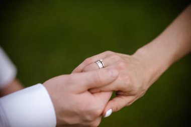 Yüzüklü gelin ve damadın elleri. Gelin ve damat bir kafede. Ahşap bir masada düğün buketi. Gelin ve damat birbirlerinin elini tutuyorlar. Evlilik yüzükleri. Bir kafede birbirini seven bir çift. Aşıklar için sıcak çay