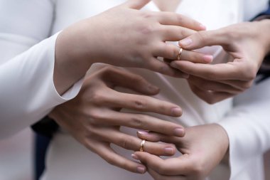 Yüzüklü gelin ve damadın elleri. Gelin ve damat bir kafede. Ahşap bir masada düğün buketi. Gelin ve damat birbirlerinin elini tutuyorlar. Evlilik yüzükleri. Bir kafede birbirini seven bir çift. Aşıklar için sıcak çay