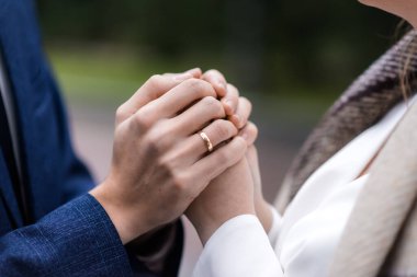 Yüzüklü gelin ve damadın elleri. Gelin ve damat bir kafede. Ahşap bir masada düğün buketi. Gelin ve damat birbirlerinin elini tutuyorlar. Evlilik yüzükleri. Bir kafede birbirini seven bir çift. Aşıklar için sıcak çay