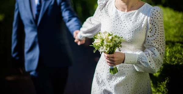白いウェディングドレスの花嫁は白い花の花束を持っています 結婚式 花嫁と新郎 ようこそ花束 異なる葉を持つ結婚式の美しい装飾 — ストック写真