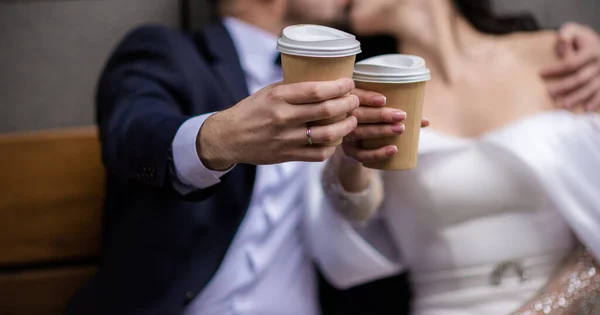 stock image hands of bride and groom with rings. bride and groom in a cafe. wedding bouquet on a wooden table. bride and groom hold each other's hands. Wedding rings. Loving couple in a cafe. hot tea for lovers