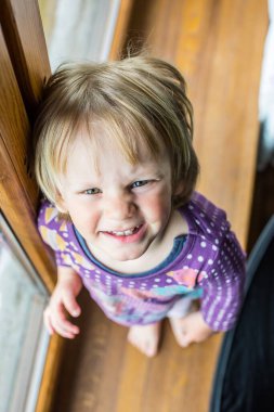 Çocuk pencere eşiğinde duruyor.