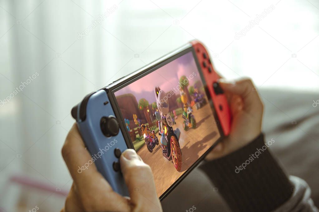 Barcelona, Dec 1st 2023: young woman playing with a Nintendo Switch portable console sitting on the sofa at home.