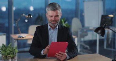 Bin yıllık yetişkin iş adamı, tablet bilgisayar kullanarak zaferi kutlarken ofis molasında gülümsüyor. Kurumsal insanlar. Teknoloji.