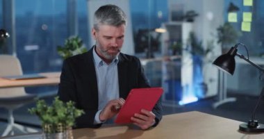 Yetişkin işadamı, tablet bilgisayar kullanıyor, oyun oynuyor, kameraya yumruk atarak zaferi kutluyor. Eğlence bürosu. Kurumsal insanlar.