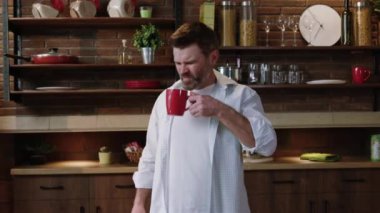 Yetişkin bir adamın portresi kahvesini yudumluyor ve evdeki mutfakta sırt ağrısı çekiyor. Sağlık sorunları ve kafein yan etkisi.